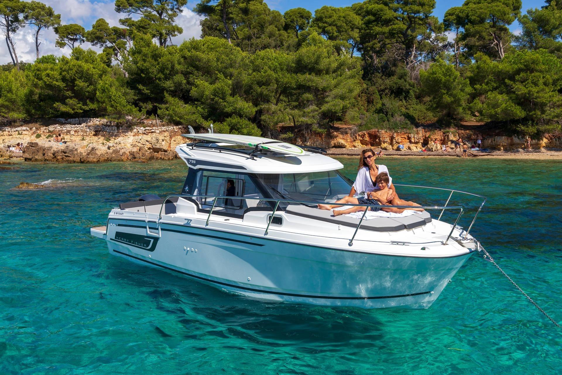 Jeanneau Merry Fisher 795 Series 2 2026 Jeanneau Merry Fisher 795 Series 2 boat on clear turquoise water near a forested shoreline.