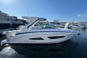 Regal 33 XO 2026 Regal 33 XO boat docked in marina, clear sky, calm water.