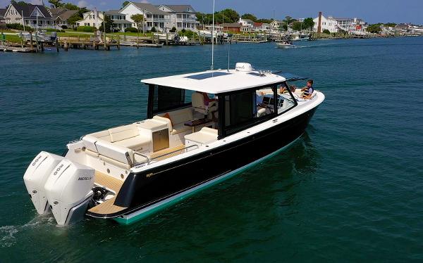 MJM 3 2026 MJM 3 boat cruising on a scenic waterfront with houses in the background.