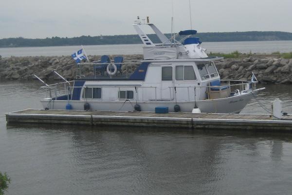Custom 370 Alcan Cruising Houseboat 1971 Custom 370 Alcan Cruising Houseboat docked by rocky shoreline.