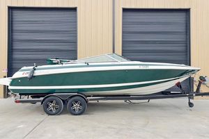 Cobalt 252 2000 Cobalt 252 boat on trailer, green and white, parked outside industrial building.