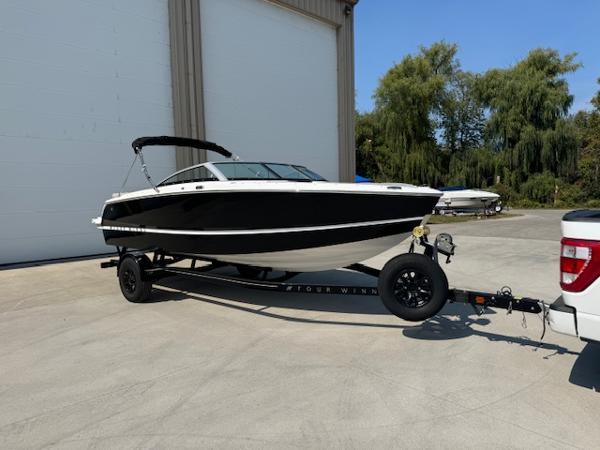 Four Winns H1 2025 Four Winns H1 boat on trailer, parked outdoors near a building.