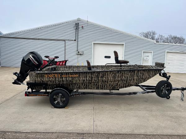 Excel 1651 River Warrior 2025 Excel 1651 River Warrior boat on trailer, camo design, parked outside a garage.