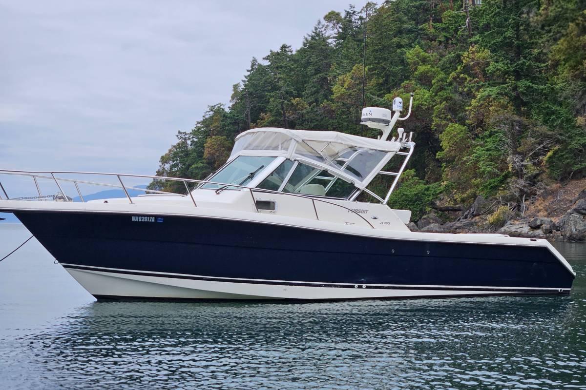 Pursuit 2860 Denali 2002 Pursuit 2860 Denali boat on calm water near forested shoreline.