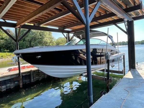 Regal 3200 Bowrider 2016 Regal 3200 Bowrider boat docked under a wooden canopy by the water.