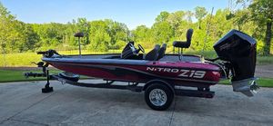 Nitro Z19 2025 Nitro Z19 boat on trailer, parked outdoors with lush greenery background.