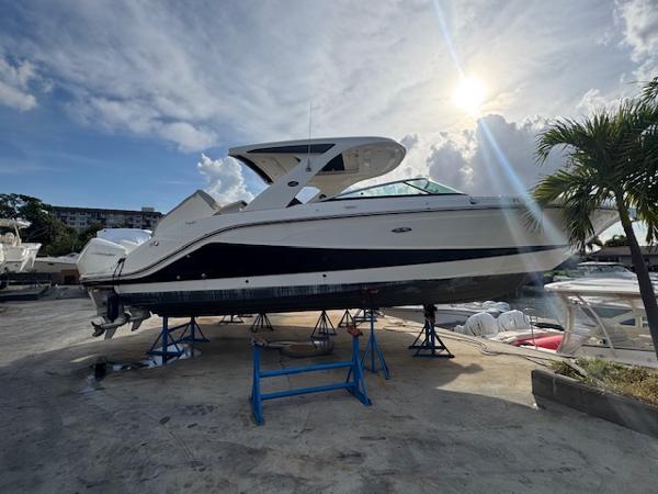 Sea Ray SLX 310 Outboard 2021 Sea Ray SLX 310 OB boat on stands, sunlit marina background.