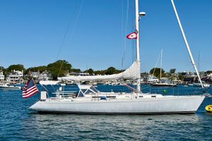 J Boats J/47, J47, J 47 Sailboat J/47 from 1991 on calm waters, with American flag, coastal town backdrop.