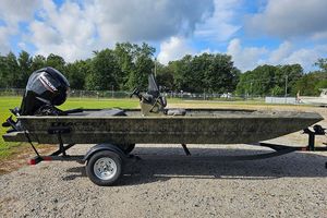 Tracker Grizzly 1860 CC 2026 Tracker Grizzly 1860 CC boat on trailer, outdoors with trees and cloudy sky.