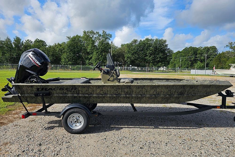 Tracker Grizzly 1860 CC 2026 Tracker Grizzly 1860 CC boat on trailer, outdoors with trees and cloudy sky.