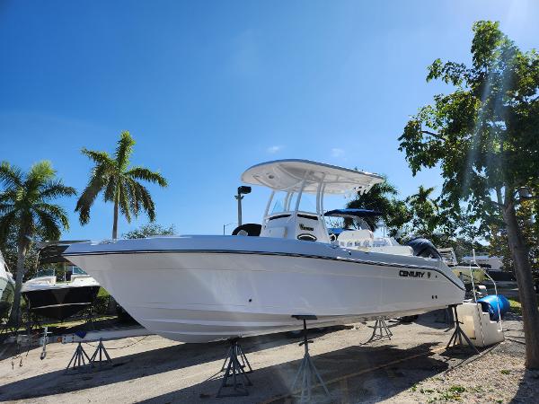 Century 2301 Center Console 2023 Century 2301 Center Console boat on stands, surrounded by palm trees under a clear blue sky.
