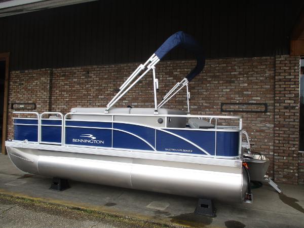 Bennington 18 SF 2024 Bennington 18 SF pontoon boat with blue and silver design, docked on land.