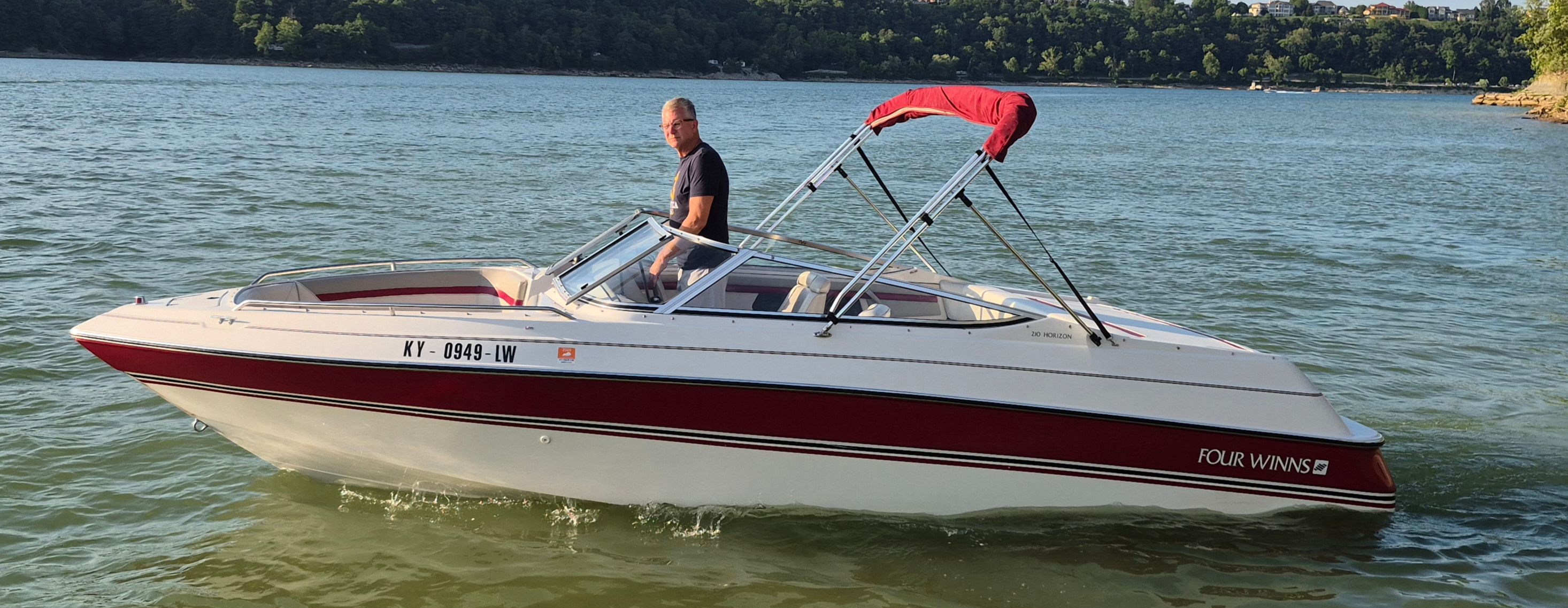 Four Winns 210 Horizon 1993 Four Winns 210 Horizon boat on a lake with a red canopy.