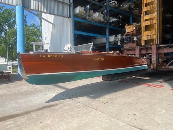 Grand Craft Classic Runabout Grand Craft Classic Runabout 2000 boat in storage, featuring a wooden hull and elegant design.