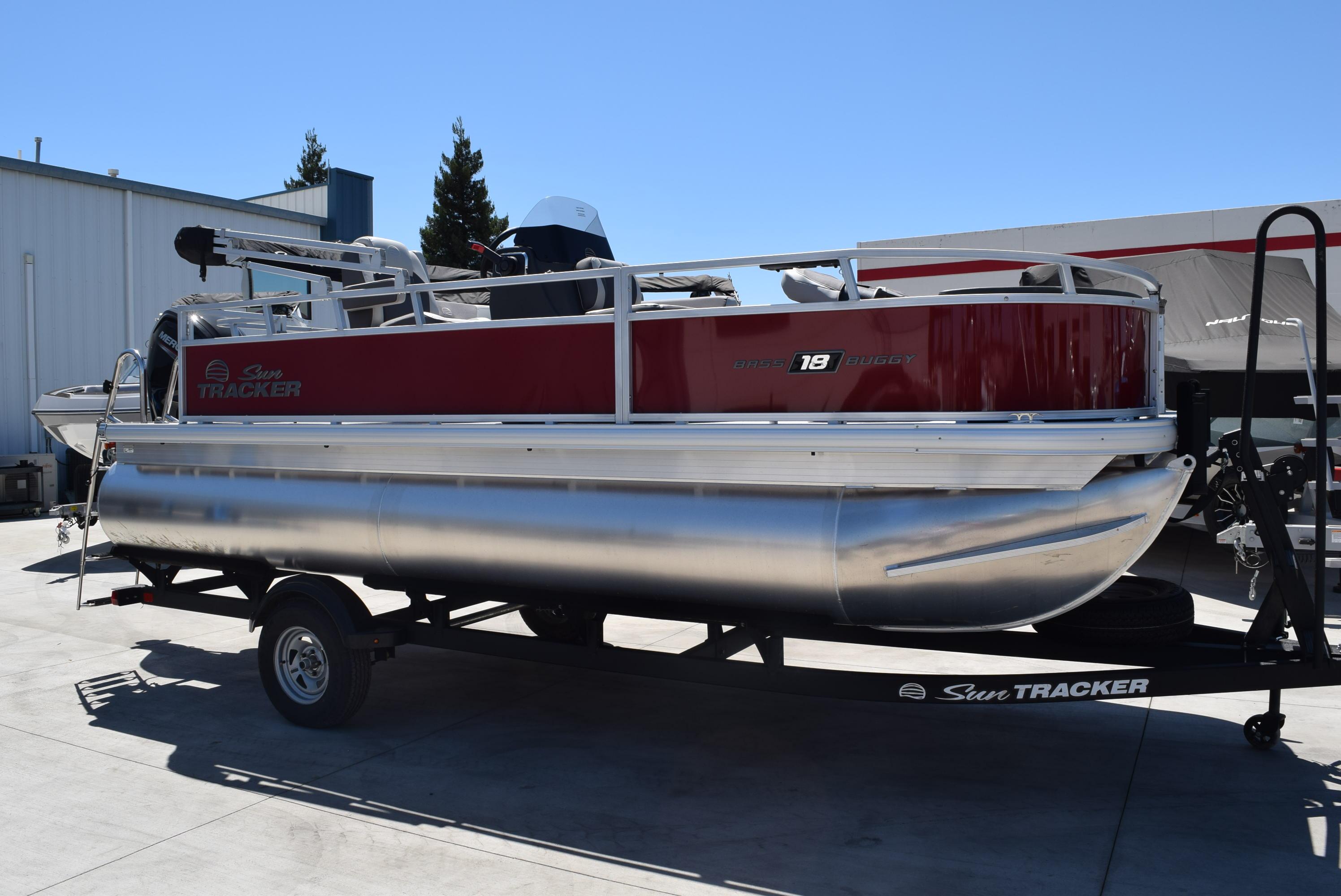 Sun Tracker Bass Buggy 18 DLX 2026 Sun Tracker Bass Buggy 18 DLX pontoon boat on trailer, parked outdoors.