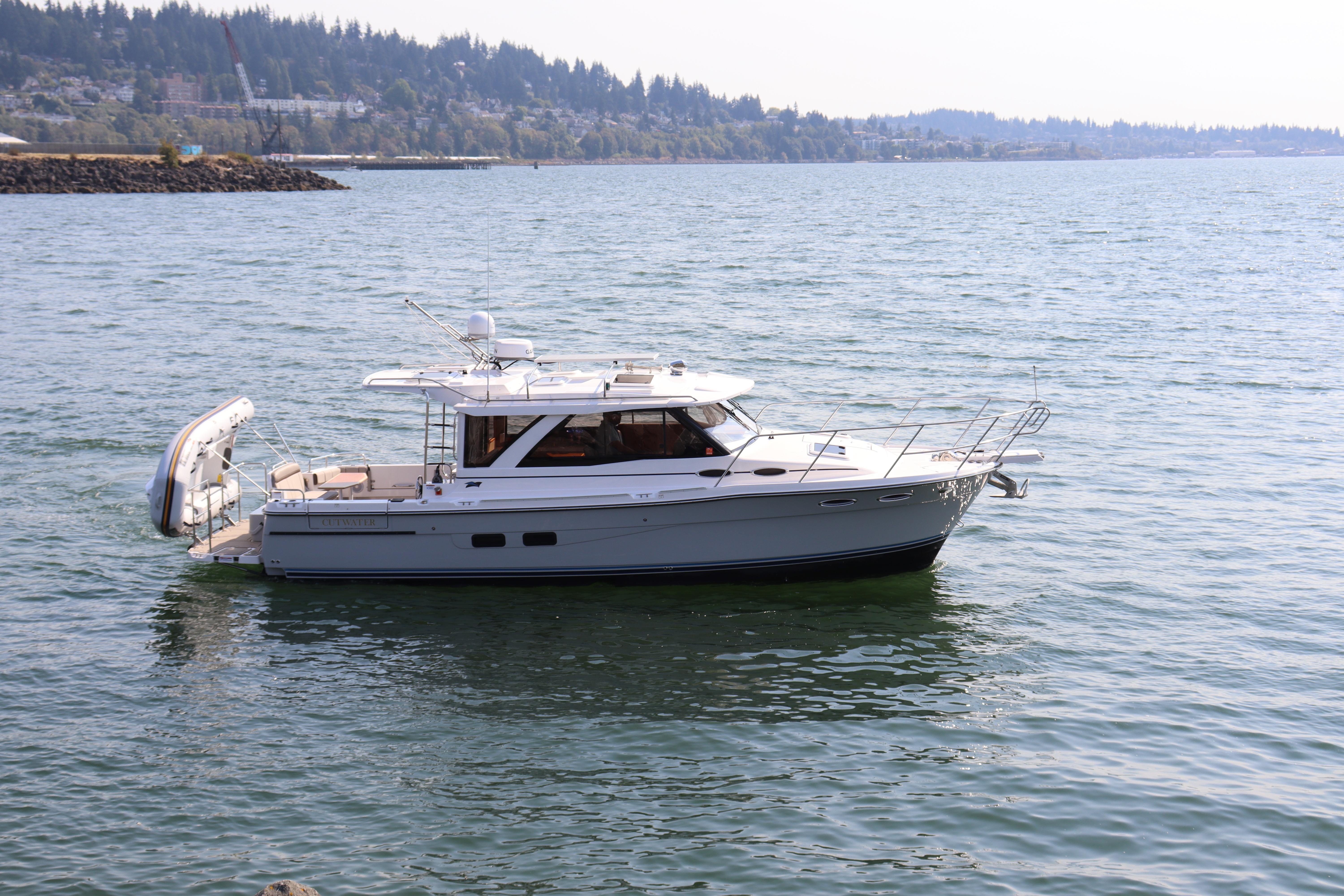 Cutwater C-30 Sedan 2024 Cutwater C-30 Sedan boat on calm water with scenic shoreline background.