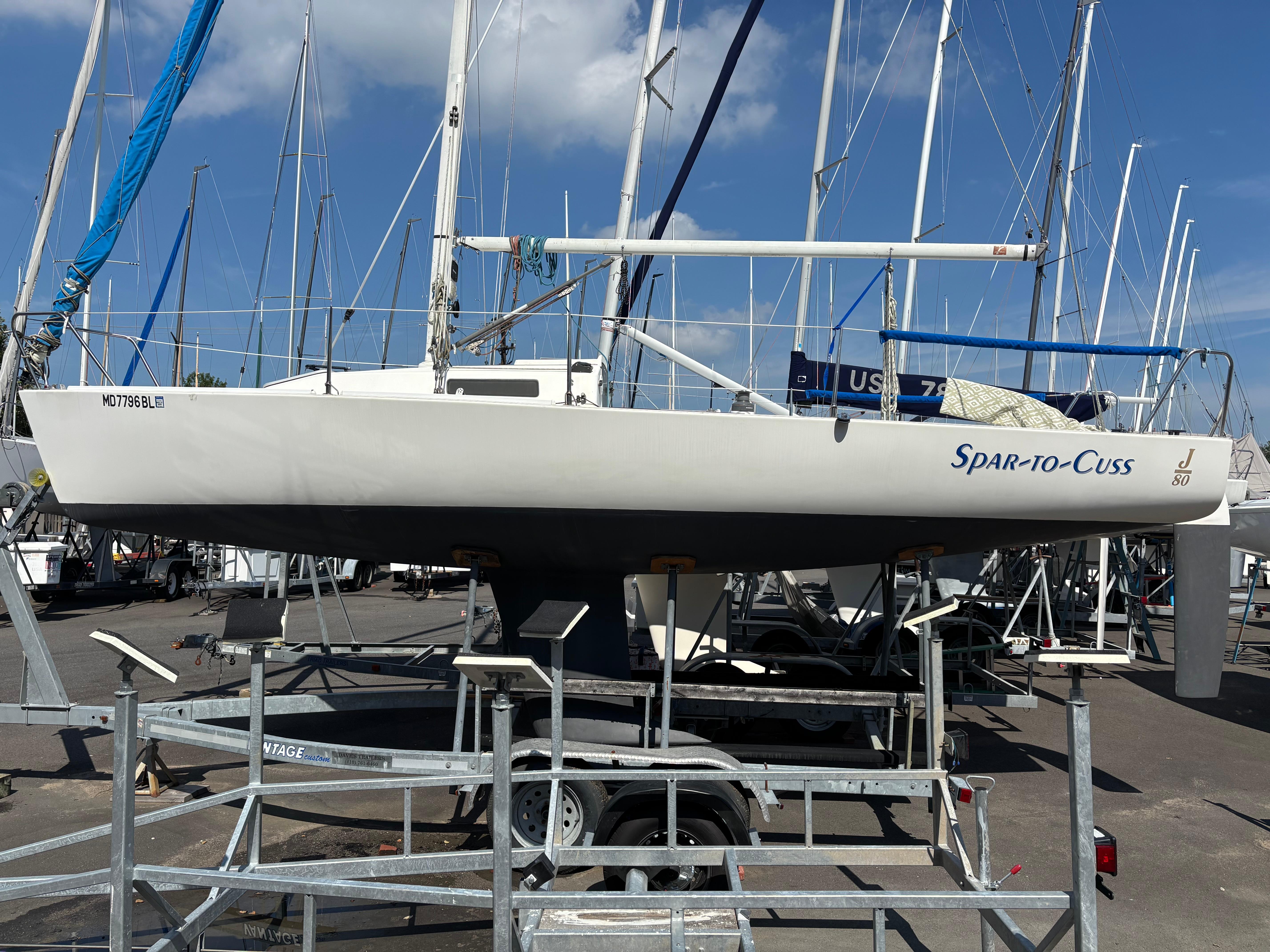 J Boats J/80 1997 J Boats J/80 sailboat on trailer, named "Spar-to-Cuss," in a marina setting.