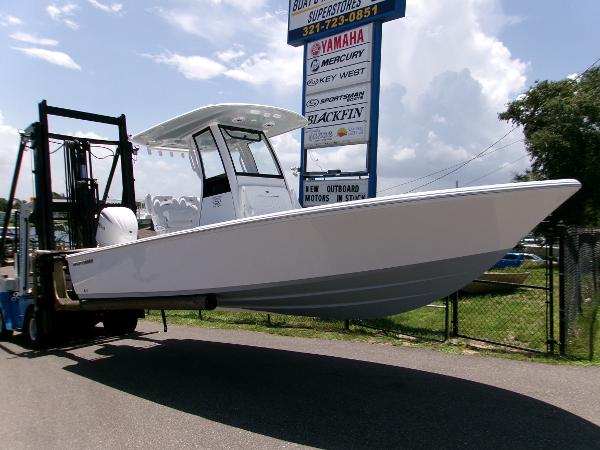 Sportsman Masters 247OE Bay Boat 2025 Sportsman Masters 247OE Bay Boat on forklift, displayed outdoors near dealership signs.