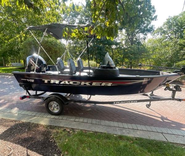 Tracker Pro Guide V-16 SC 2025 Tracker Pro Guide V-16 SC boat on trailer, parked outdoors under trees.