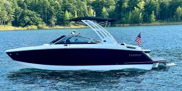 Cobalt R6 2024 Cobalt R6 boat cruising on a lake with forested shoreline.