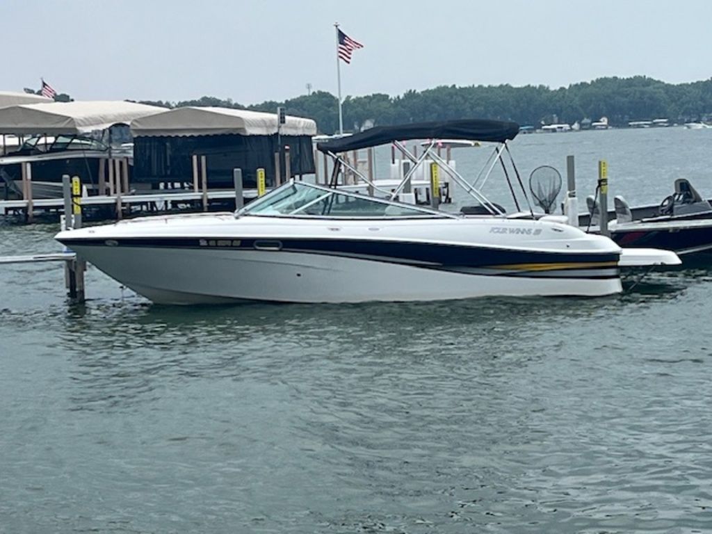 Four Winns 240 Horizon 2002 Four Winns 240 Horizon boat docked on a lake with American flag.