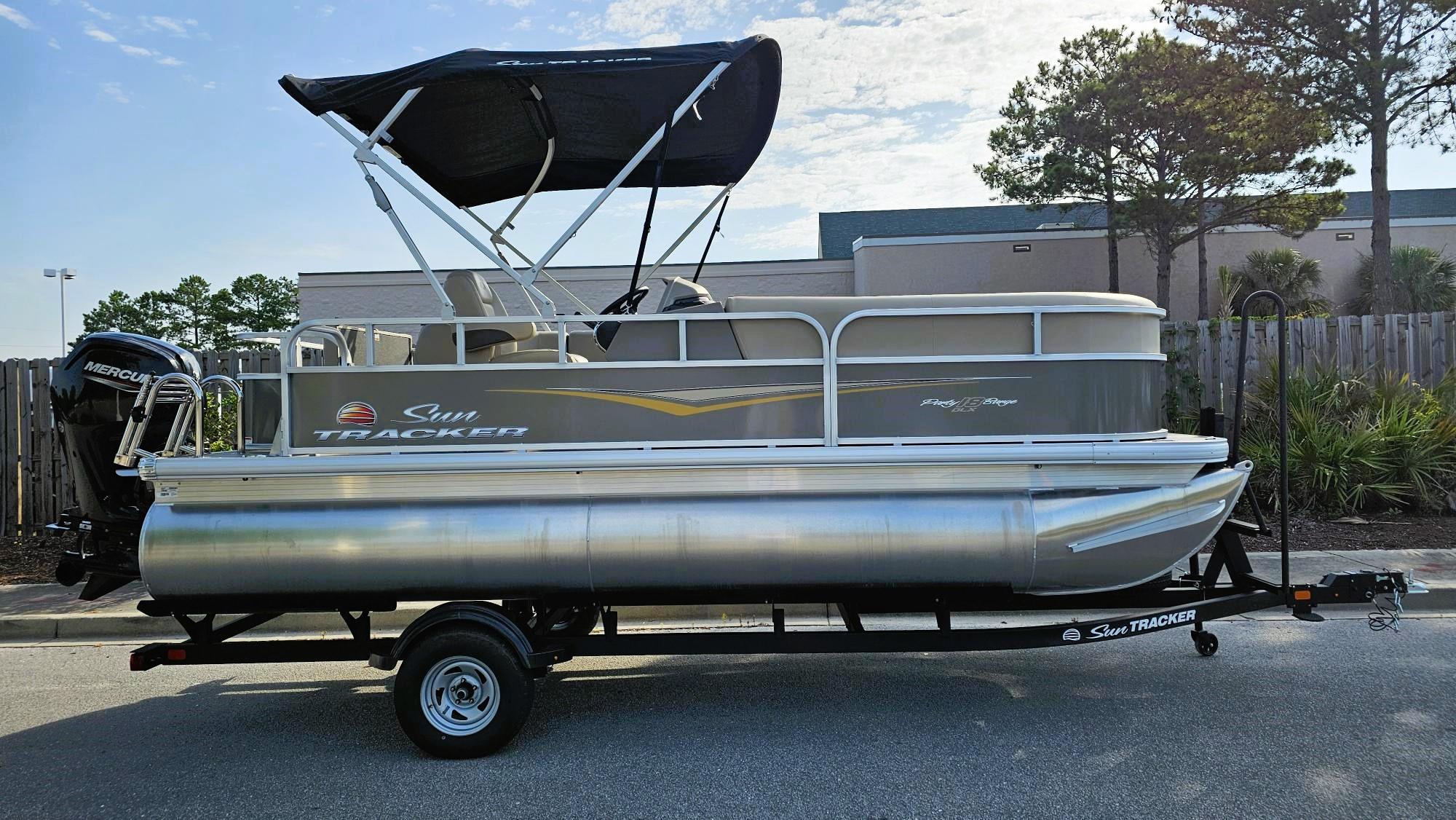 Sun Tracker Party Barge 18 DLX 2025 Sun Tracker Party Barge 18 DLX pontoon boat on trailer, parked outdoors.