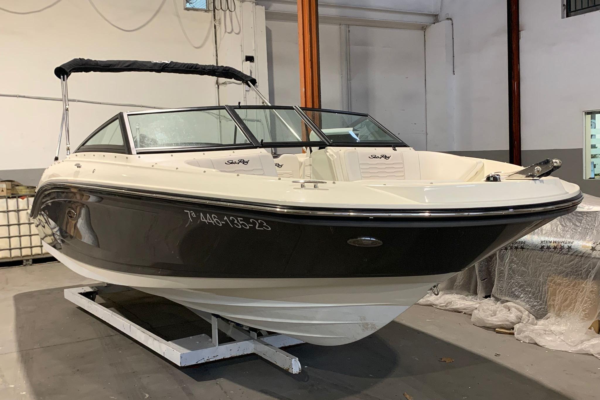 Sea Ray SPX 210 Outboard 2023 Sea Ray SPX 210 Outboard boat in a showroom, featuring sleek black and white design.