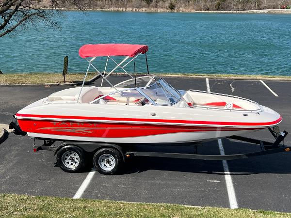 Tahoe 204 WT 2006 Tahoe 204 WT boat with red accents and canopy, parked near a lake.