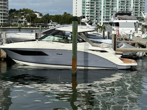 Sea Ray Sundancer 320 2019 Sea Ray Sundancer 320 docked at marina with modern buildings in background.