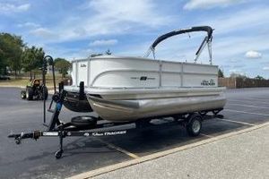 Sun Tracker Party Barge 16 DLX 2026 Sun Tracker Bass Buggy 16 DLX pontoon boat on trailer in parking lot.