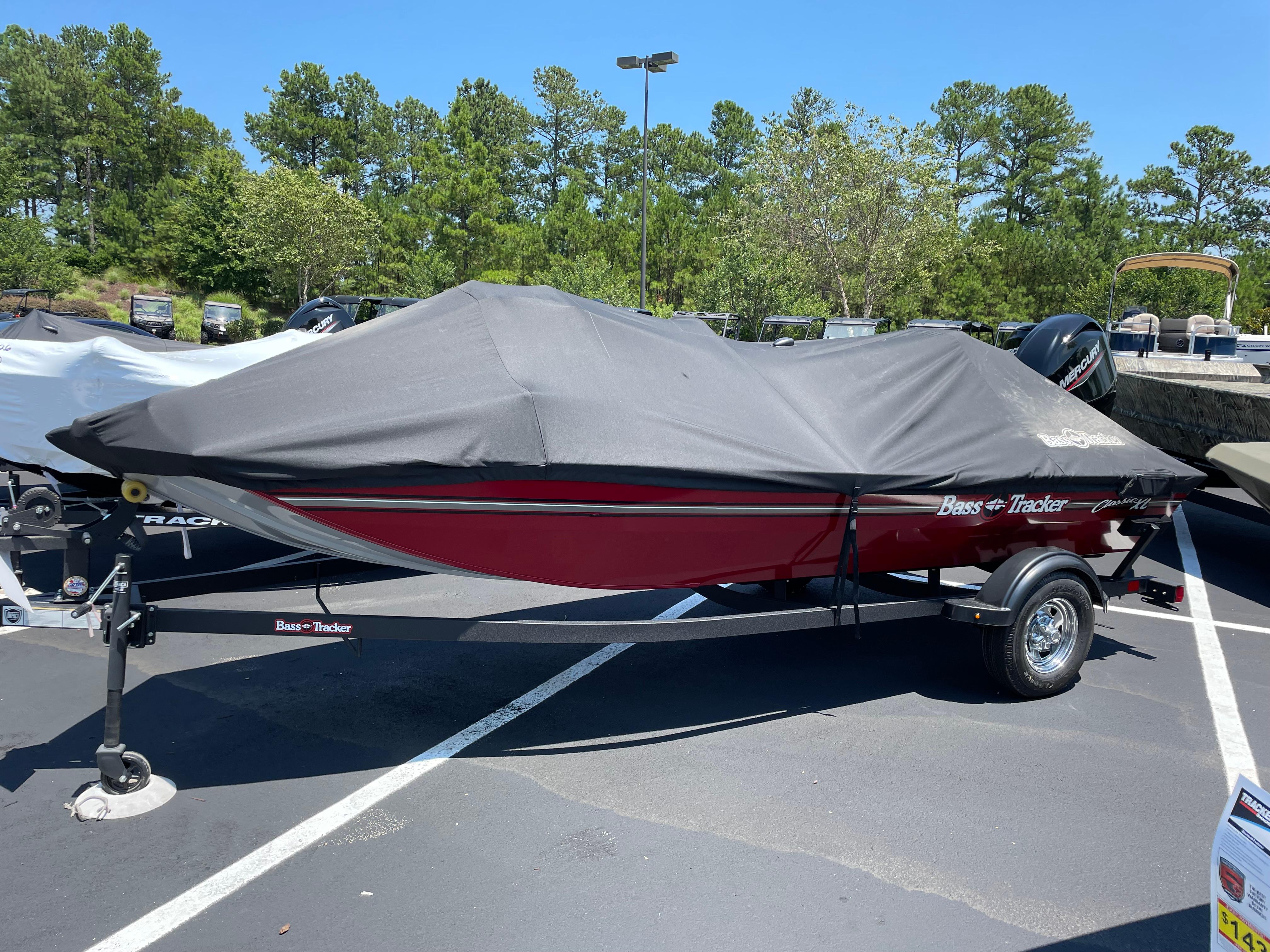 Tracker Pro 170 2025 Tracker Pro 170 boat with cover in parking lot, surrounded by trees.