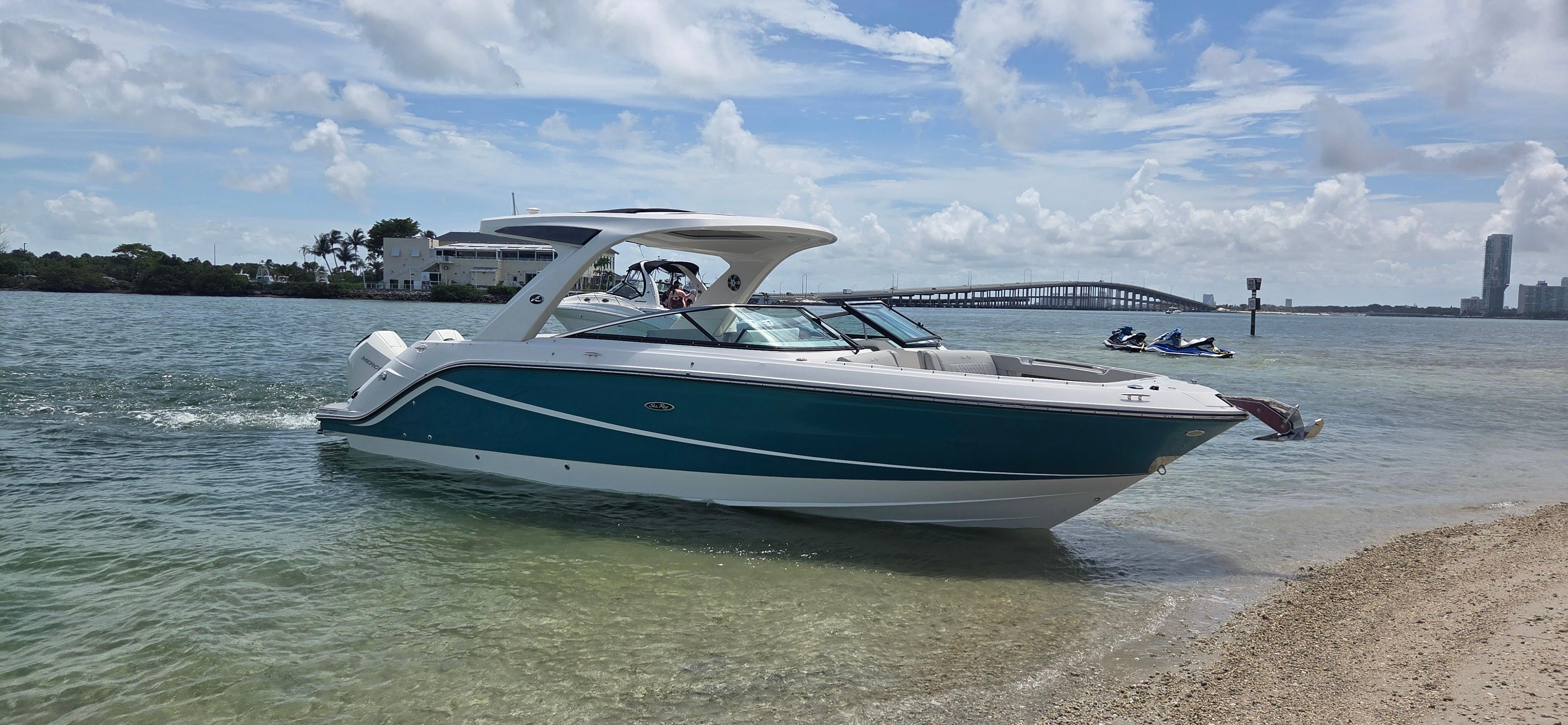 Sea Ray SLX 310 Outboard 2021 Sea Ray SLX 310 Outboard boat on calm waters near a sandy shore.