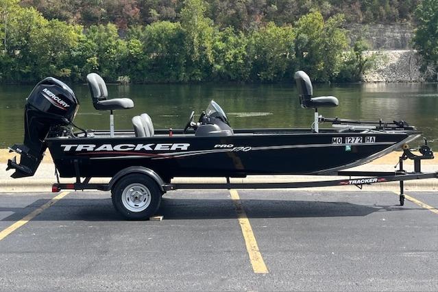 Tracker Pro 170 2024 Tracker Pro 170 boat on trailer by a river, featuring Mercury outboard motor.