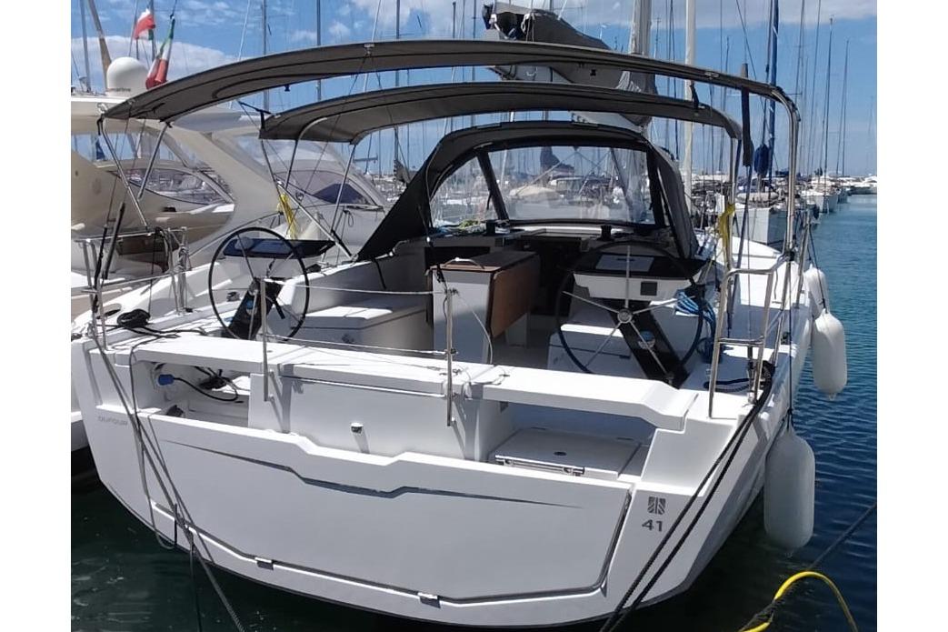 Dufour 41 2025 Dufour 41 yacht docked at marina, featuring dual steering wheels and spacious cockpit.