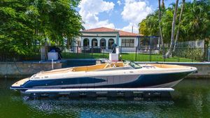 Chris-Craft Launch 32 2013 Chris-Craft Launch 32 boat docked by a waterfront home, surrounded by lush greenery.