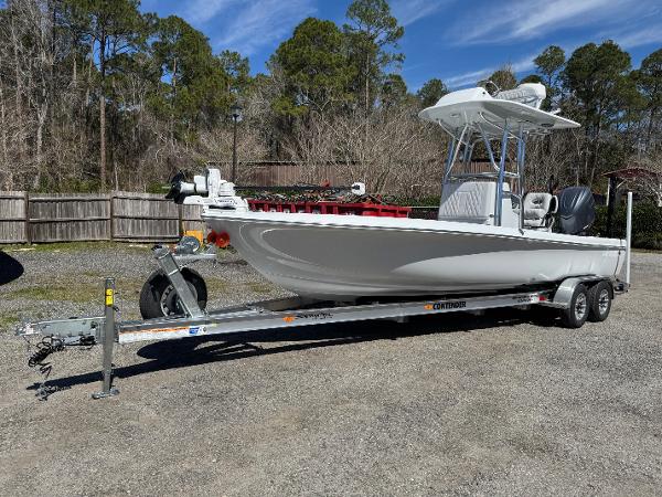 Contender 26 Bay 2025 Contender 26 Bay boat on trailer, parked outdoors with trees in the background.