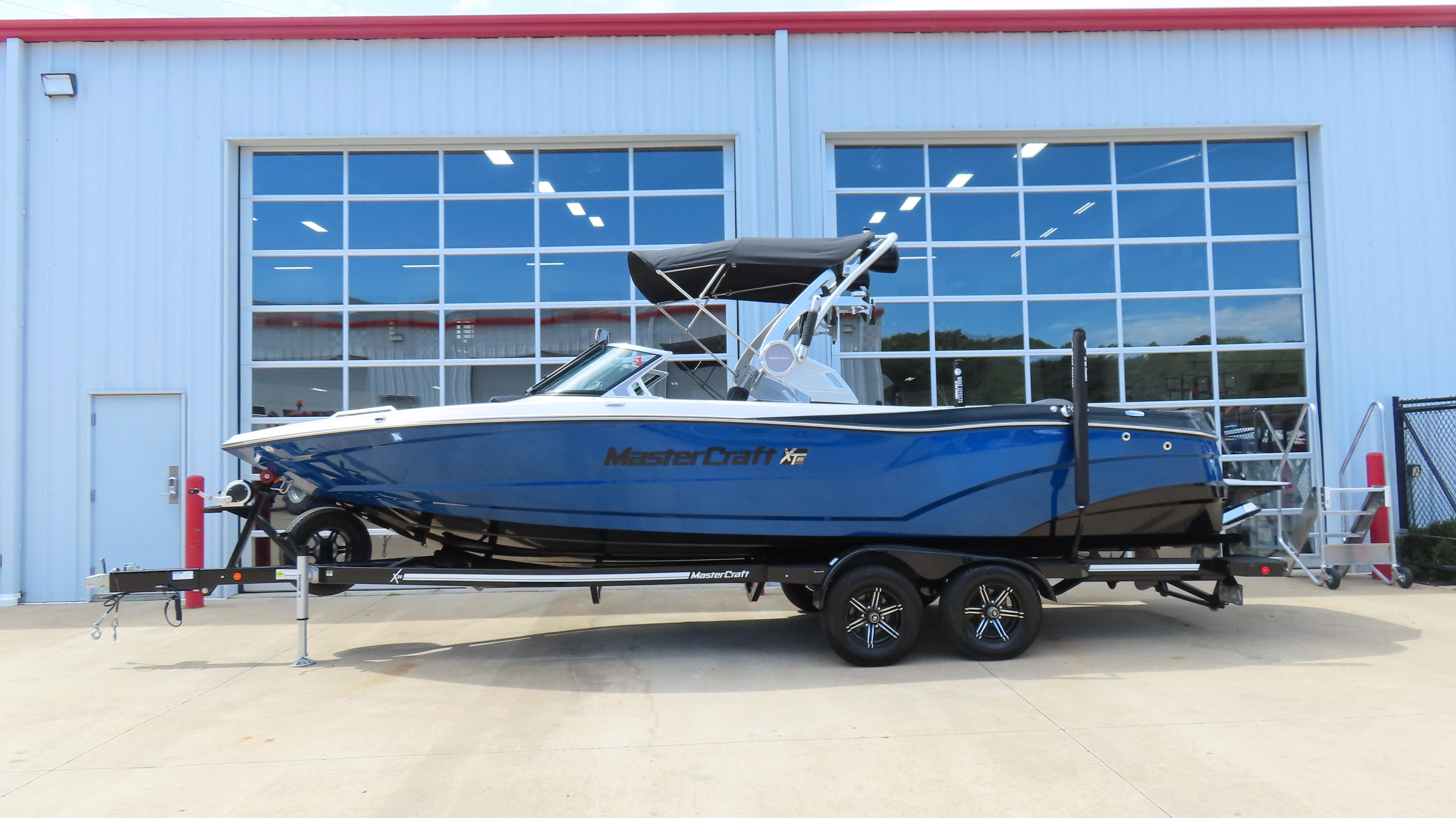 MasterCraft XT25 2019 MasterCraft XT25 boat on trailer, parked outside a building with large windows.