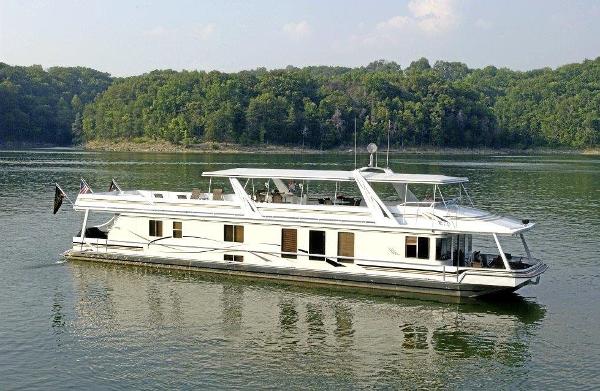 Stardust Cruisers Houseboat 2002 Stardust Cruisers houseboat on a serene lake with lush green forest backdrop.