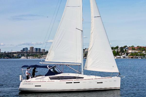 Jeanneau 41 Deck Salon 2013 Jeanneau 41 Deck Salon sailboat cruising on a calm lake with cityscape background.