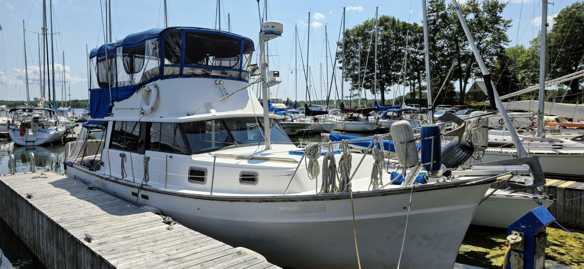 Mainship 35 Trawler 1977 Mainship 35 Trawler docked at a marina, surrounded by sailboats and clear skies.