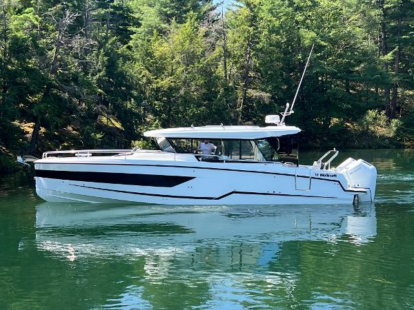 Wellcraft 355 Commuter 2024 Wellcraft 355 Commuter boat on a serene lake surrounded by lush trees.