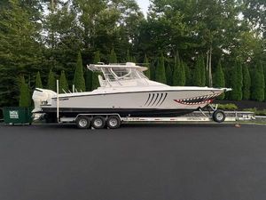 Contender 36 Fisharound 2005 Contender 36 Fisharound boat on trailer with shark mouth design, parked on asphalt.