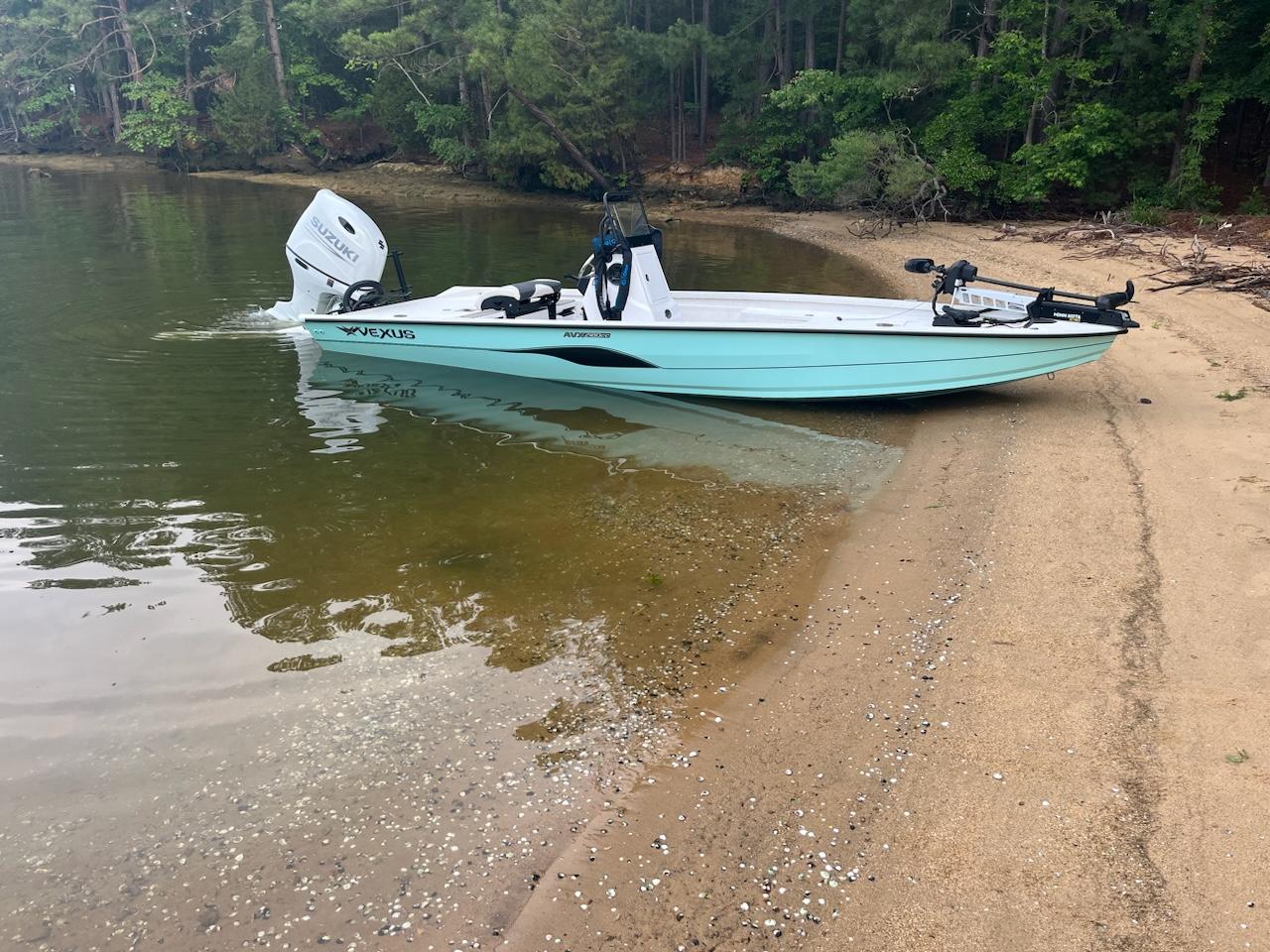 Vexus AVX2180CC 2023 Vexus AVX2180CC boat on sandy shore, surrounded by trees and calm water.