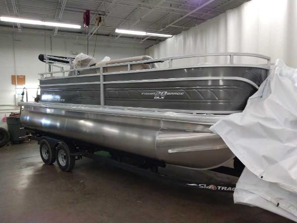 Sun Tracker Fishin' Barge 20 DLX 2025 Sun Tracker Fishin' Barge 20 DLX pontoon boat in a showroom.