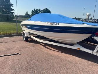 Bayliner 205 Bowrider 2005 Bayliner 205 Bowrider boat on trailer with blue cover, parked outdoors.