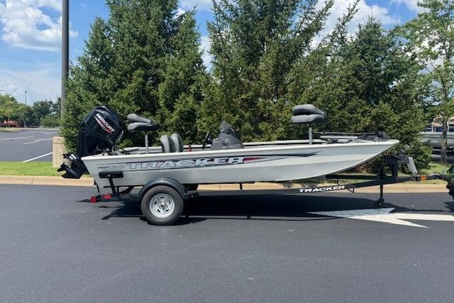 Tracker Pro 170 2026 Tracker Pro 170 boat on trailer, parked outdoors, surrounded by trees.