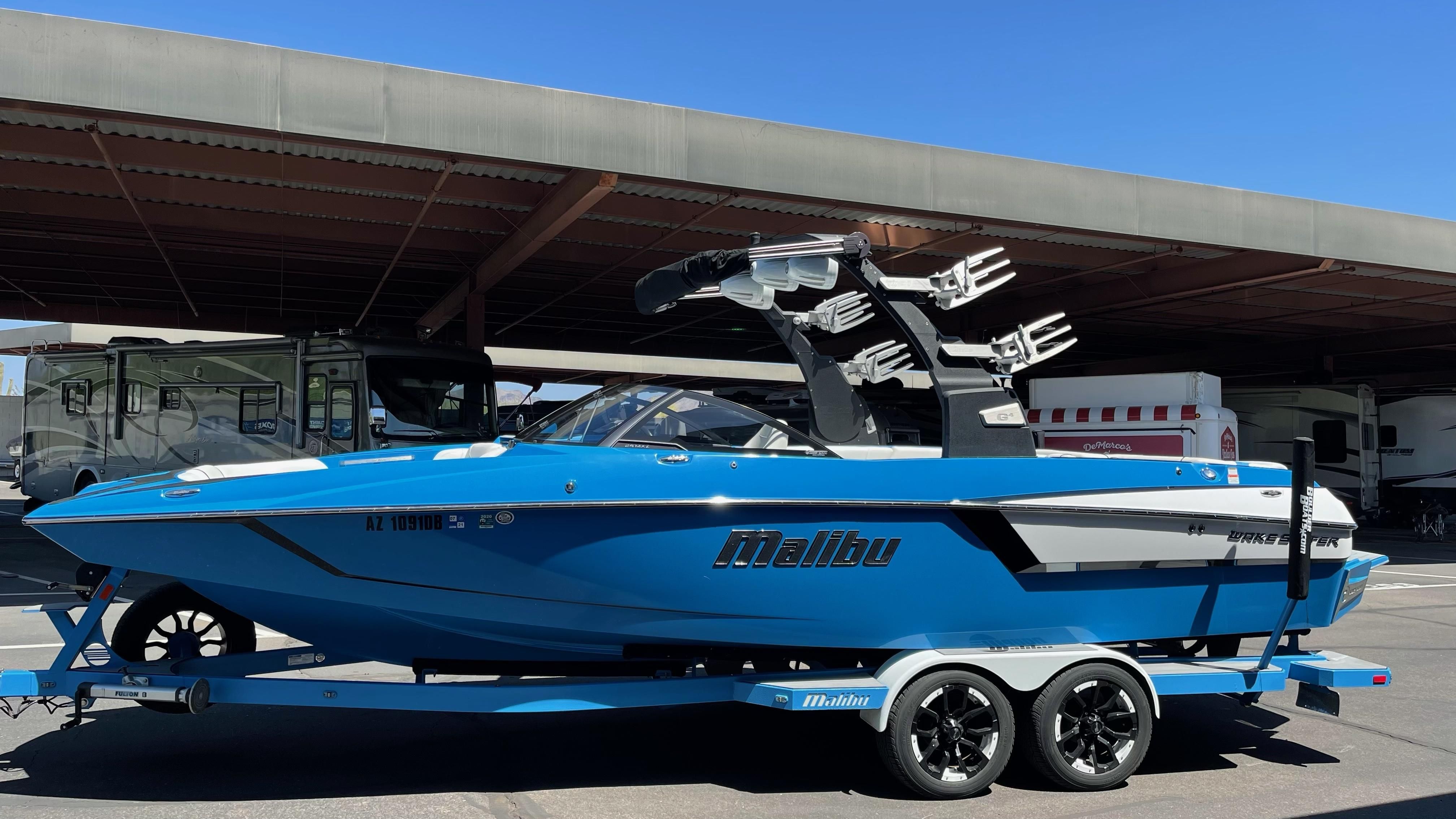 Malibu Wakesetter 24 MXZ 2017 Malibu Wakesetter 24 MXZ boat in blue, parked on a trailer under a canopy.