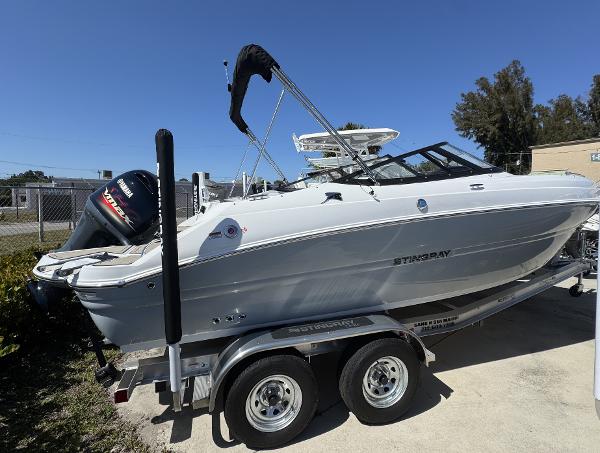 Stingray 211DC 2025 Stingray 211DC boat on trailer, white exterior, parked outdoors under clear blue sky.