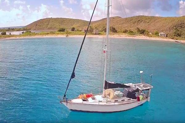 Tartan 40 Sailboat Tartan 40 (1989) anchored in clear blue water near a scenic coastline.