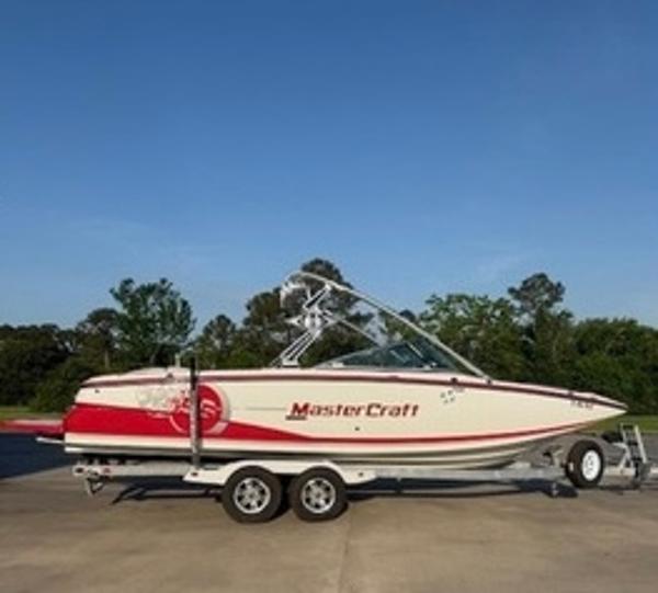 MasterCraft X55 2010 MasterCraft X55 boat on trailer, red and white design, parked outdoors.